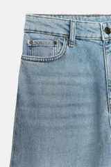 Jeans wide leg de tiro alto y diseño de cinco bolsillos, con efecto lavado, trabillas en la cintura y cierre frontal con cremallera y botón metálico.