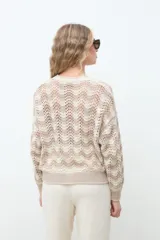 Campera de punto abierta con botones frontales, cuello redondo y mangas largas, con diseño geométrico en tonos crudo y beige.