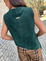 Top verde oscuro de gamuza con cuello buche, diseño sin mangas, corte asimétrico y flecos diagonales en el frente.