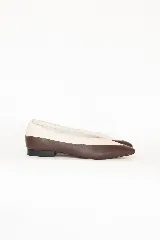 Chatitas de cuero con diseño bicolor, combinando tonos chocolate y off-white. Presentan una silueta de punta fina y un taco bajo de bloque.
