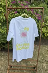 Remera de manga corta color blanco, con diseño estampado en el frente que muestra una copa de cóctel con una rodaja de limón y el texto 'Última ronda' en color amarillo.