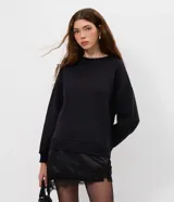 Buzo de algodón con felpa, corte oversized, cuello redondo y mangas largas. Presenta un detalle de encaje aplicado en el ruedo, aportando un contraste femenino y sofisticado.
