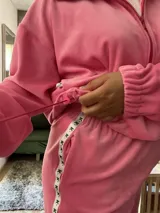 Buzo oversize de plush color rosa chicle, con cuello alto, cierre frontal parcial, capucha y bolsillo tipo canguro. Presenta puños elásticos y cordón ajustable en el ruedo.