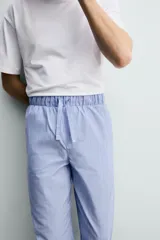 Set de pijama para hombre compuesto por una remera blanca de cuello redondo y mangas cortas, y un pantalón celeste a rayas verticales con cintura elástica y bolsillos laterales.
