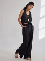 Pantalón negro de lino, de corte clásico con pierna recta y tajos laterales en el ruedo. La cintura es elastizada.