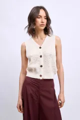 Chaleco de punto color marrón, con escote en V y cierre frontal con botones dorados.