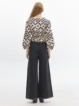 Blusa crop de denim con estampado a cuadros en tonos beige y negro, de manga larga abullonada con puños elásticos y escote en V.