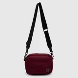 Bandolera Bubba modelo Purse color bordó, de diseño acolchado y compacto, con cierre superior y correa ajustable de cinta negra con logo estampado.