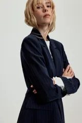 Blazer entallado de color azul marino con estampado de rayas diplomáticas, cuello con solapa, hombreras, manga larga y cierre frontal con un botón. Cuenta con bolsillos delanteros con solapa.