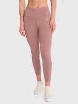 Calza deportiva de tiro alto con largo hasta el tobillo, confeccionada en tejido elástico de color rosado tierra. Presenta un diseño minimalista sin bolsillos y un pequeño logo bordado en la cadera.
