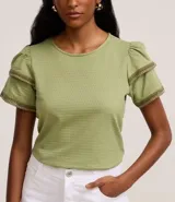 Blusa de manga corta color verde, con cuello redondo y detalles de terminación en efecto ganchillo en las mangas. Confeccionada en tejido de algodón con textura sutil.