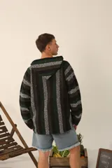 Buzo canguro con capucha y bolsillo frontal estilo canguro, tejido a rayas en tonos negro, verde y blanco.