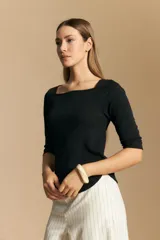 Remera de rib color negro con escote cuadrado y mangas tres cuartos. Confeccionada en tejido acanalado elástico que se adapta al cuerpo.