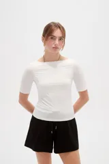Remera de poliamida color blanco, de corte ajustado al cuerpo, con mangas 3/4 y cuello redondo a la base.