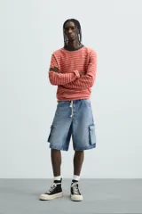 Bermuda de denim de algodón, color celeste lavado, de corte relajado (relaxed fit). Presenta cinco bolsillos, incluyendo bolsillos cargo plastrón con solapa en las perneras.