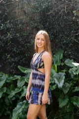 Vestido corto negro con estampado de plumas doradas, escote en V, breteles finos cruzados en la espalda, cut-outs laterales y volado en el ruedo.