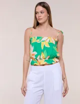 Top crop de rayón con estampado floral tropical en tonos verdes, amarillos y blancos. Presenta escote recto, frunces elastizados en el pecho y la cintura, y tirantes finos para anudar en los hombros.