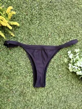 Conjunto de bikini negro texturizado, con corpiño en V y bombacha colaless regulable.