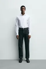 Camisa de corte regular fit confeccionada en tejido de algodón con textura. Presenta cuello italiano, manga larga con puños abotonados y cierre frontal de botones.