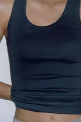 Top negro de corte ajustado (slim fit) con escote redondo y manga sisa.