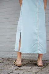 Vestido midi celeste de corte recto, sin mangas y con costuras verticales en contraste color salmón.