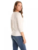 Buzo de tejido fino en color blanco, con cuello redondo y mangas tres cuartos tipo raglán. Presenta un detalle decorativo de tachas metálicas a lo largo de las mangas.