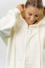 Campera deportiva con capucha de corte oversize, confeccionada en tejido suave con interior forrado en piel sintética. Presenta cierre frontal completo, bolsillos laterales y capucha amplia con cordones largos ajustables.