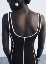Vestido midi de algodón color marrón con diseño de rayas verticales en relieve de color blanco. Presenta cuello escotado, tirantes anchos y un corte recto.
