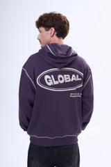 Buzo tipo canguro oversize color violeta oscuro con capucha, bolsillo delantero y estampa gráfica en la espalda con la palabra 'GLOBAL'. Presenta costuras decorativas en contraste.