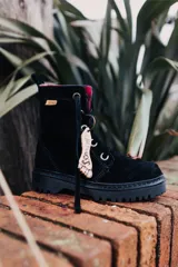 Bota acordonada de cuero color negro con interior a cuadros rojos y negros.