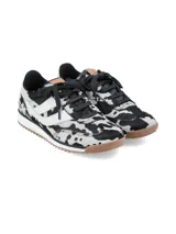 Championes urbanos con diseño de estampado animal print tipo vaca en blanco y negro, con detalles en blanco en los laterales, cordones negros y suela de goma dentada en color marrón.