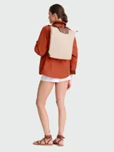 Mochila de diseño icónico con cuerpo de lona resistente en color beige y detalles de cuero marrón en la solapa superior y correas. Cuenta con cierre de cremallera, solapa con botón a presión y correas ajustables para los hombros.