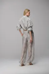 Conjunto de dos piezas compuesto por una chaqueta corta tipo crop con cordón ajustable en el ruedo y un pantalón de corte recto. Ambas prendas están confeccionadas en tela de organza con estampado floral tipo damasco en tonos grisáceos.