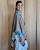 Ruana de tejido de punto en color crema con detalle de estrella grande en color verde lima en la espalda y bordes en tono arena.