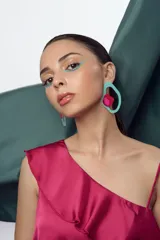 Par de aros colgantes con forma orgánica, compuestos por una estructura de acrílico celeste y una pieza superpuesta de acrílico rojo con detalle rosa.