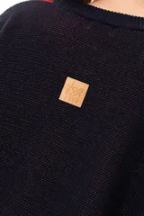 Buzo tejido de punto con silueta oversize y calce relajado. Presenta un diseño gráfico inspirado en una granada con bloques de color en azul marino, rojo y beige, cuello redondo y terminaciones en rib.