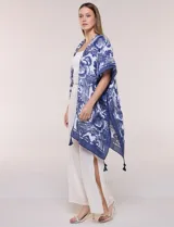 Kimono de gasa ligera con estampado floral en tonos de azul y blanco, silueta amplia, mangas cortas y detalle de borlas en el ruedo asimétrico.