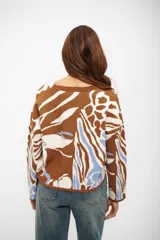 Saco de punto con escote en V y cierre frontal de botones. Presenta un diseño estampado con formas abstractas en tonos marrón, blanco y celeste.