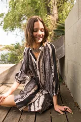 Vestido camisero con cuello a la base y mangas al codo, con botones al frente y estampado tie dye en tonos grises y blancos.