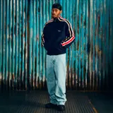 Campera de punto tipo cardigan con cierre frontal, color azul marino. Presenta franjas laterales multicolores en las mangas y logo bordado en el pecho.