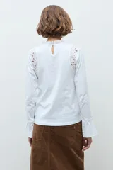 Remera de manga larga color terracota, con cuello alto y detalles de broderie en los hombros y puños acampanados.