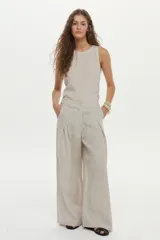 Pantalón de lino color beige, de pierna amplia, con elástico en la cintura, pinzas en el frente y bolsillos laterales y traseros.