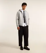Campera bomber con capucha confeccionada en tejido técnico estructurado. Presenta cierre frontal con cremallera, bolsillos laterales y puños y cintura con elástico. Diseño versátil de corte estándar.