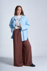 Sobrecamisa color beige confeccionada en gabardina, de corte holgado, con cuello camisero, cierre frontal con botones, dos bolsillos de parche en el pecho y mangas largas con puños abotonados.