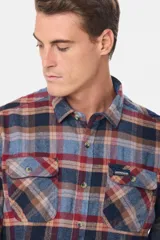 Sobrecamisa de viyela gruesa con diseño de cuadros en tonos azul y bordó. Cuenta con cuello clásico, cierre frontal con botones y dos bolsillos delanteros con solapa y botón.