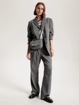 Bandolera gris con solapa y cierre a presión. Presenta una correa ajustable y una cadena dorada gruesa en la parte delantera con el monograma TH.