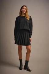 Sweater tejido color marrón claro, de escote redondo y calce holgado. Tiene hombros caídos, mangas largas y puños tejidos.