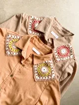 Chemise de algodón tusor con cuello clásico y mangas largas, con detalles artesanales de parches tejidos al crochet en los hombros.
