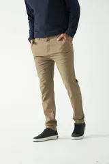 Pantalón chino color beige, de corte slim, con bolsillos laterales y traseros. Se ajusta a la cintura con cinturón de cuero marrón.