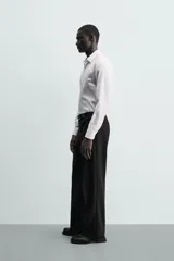 Camisa de corte slim fit confeccionada en tejido de algodón. Presenta cuello italiano, manga larga con puños abotonados y cierre frontal mediante botonadura clásica.